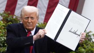 President Donald Trump sits in the White House Rose Garden, holding up an executive order he has just signed. | Abaca Press/Gripas Yuri/Abaca/Sipa USA/Newscom